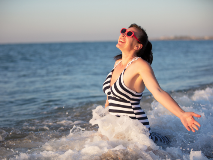Vrouw in badpak staat vrolijk in de zee