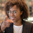 vrouw kijkt lachend in de camera met een wijzende vinger