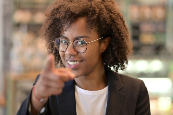 vrouw kijkt lachend in de camera met een wijzende vinger