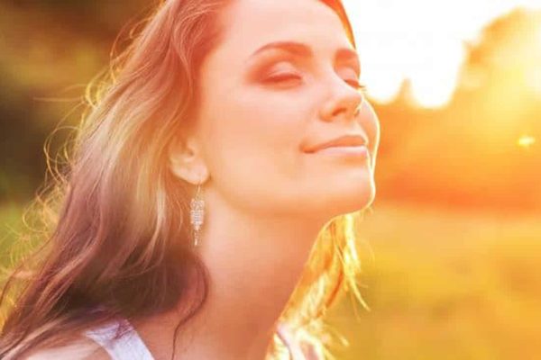 vrouw kijkt in de zon met gesloten ogen en oogt tevreden en blij|Young woman on field under sunset light|een houten tafel met twee dumbbells
