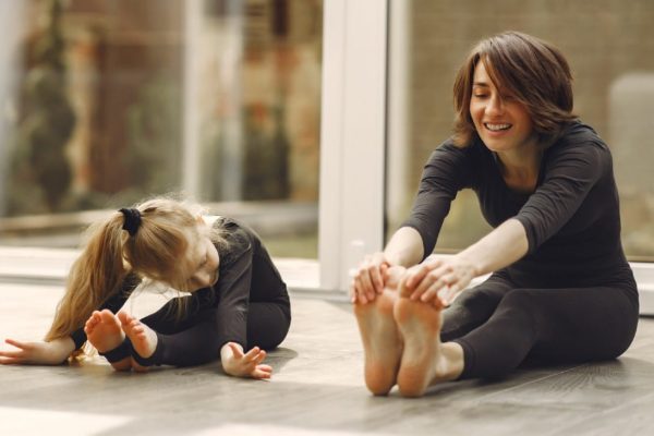 vrouw en jong meisje doen samen een stretchoefening