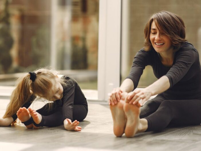 vrouw en jong meisje doen samen een stretchoefening