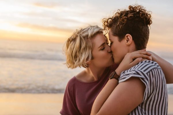 twee vrouwen kussen elkaar op het strand