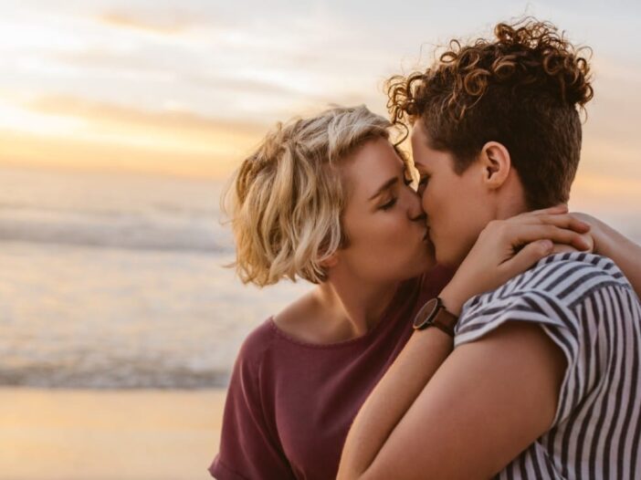 twee vrouwen kussen elkaar op het strand