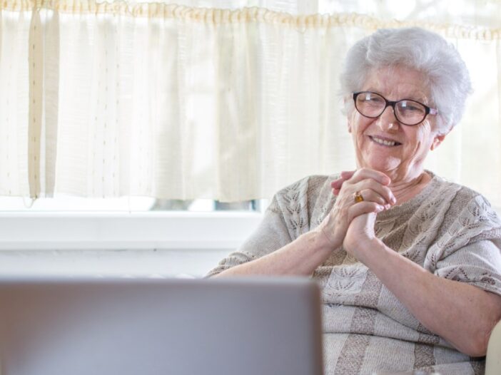 oudere vrouw maakt gebruik van laptop en lacht