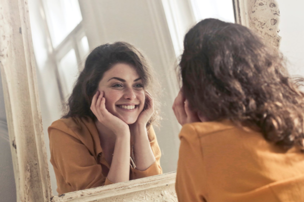 Vrouw kijkt blij naar zichzelf in spiegel