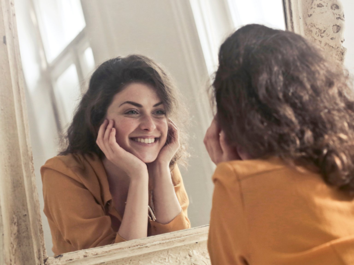 Vrouw kijkt blij naar zichzelf in spiegel