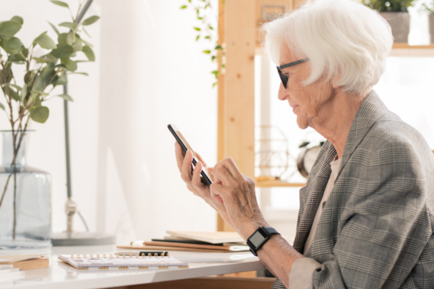 oudere vrouw met bril zit op mobiele telefoon