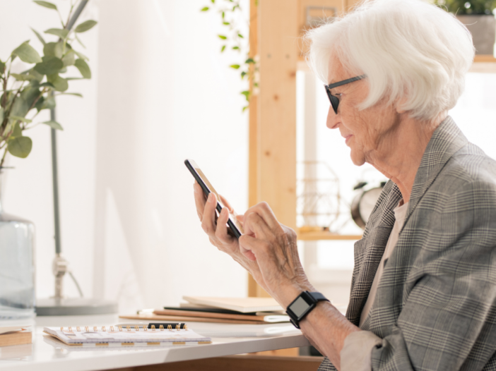 oudere vrouw met bril zit op mobiele telefoon