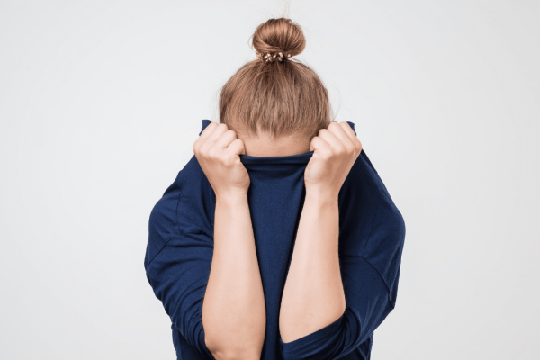 vrouw verstopt haar gezicht in haar trui