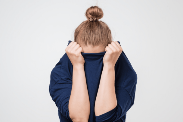 vrouw verstopt haar gezicht in haar trui