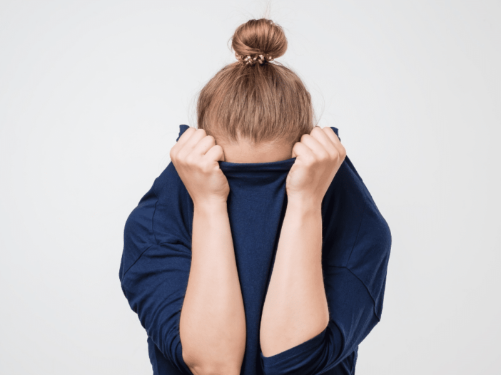 vrouw verstopt haar gezicht in haar trui