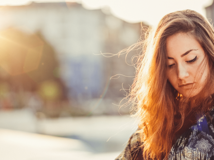 vrouw zit buiten in de zon en kijkt naar beneden|vrouw zit in de auto met zonnebril en kijkt gestresst