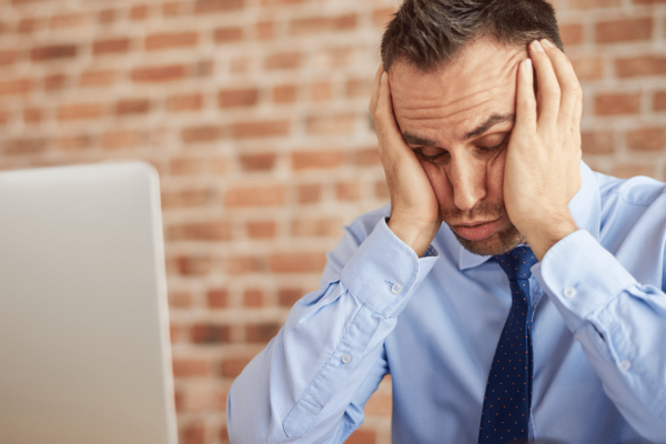 man achter laptop heeft last van stress