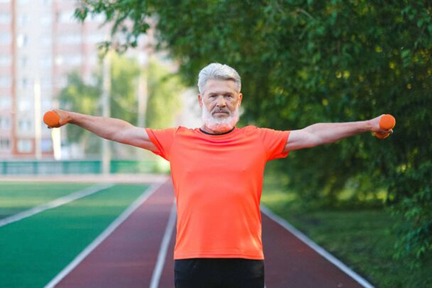 Man met twee dumbbells staat op spotveld