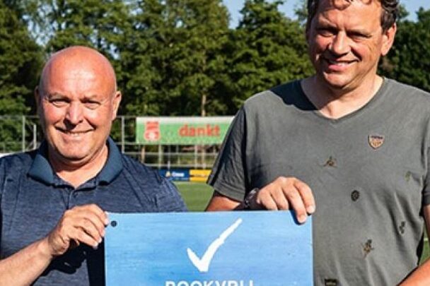 Twee mannen op een sportveld houden een bord vast met daarop een vinkje en de tekst rookvrije generatie