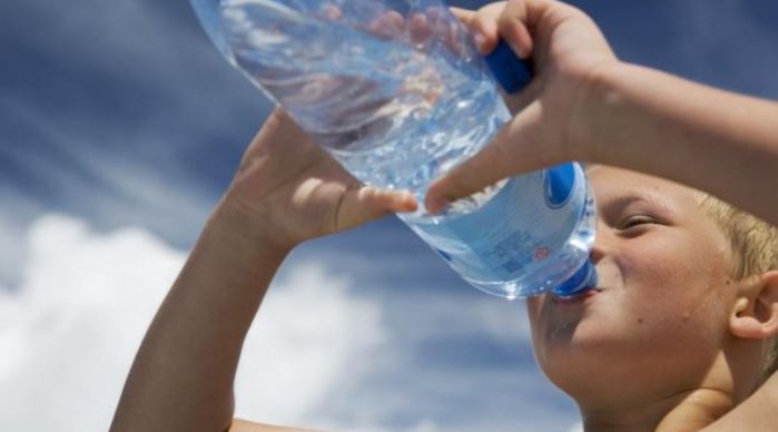 Jongen drink water uit fles