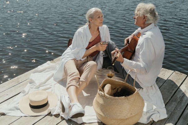 man en vrouw zitten samen op een picknickkleed aan het water