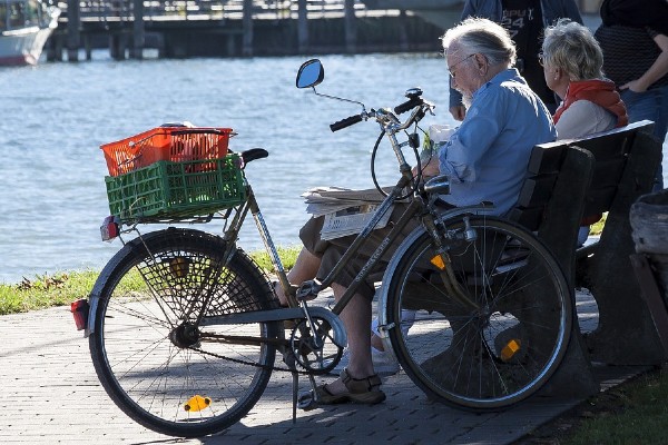 twee ouderen zitten samen op een bankje na het fietsen