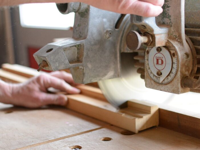 man gebruikt zaagmachine voor houten plank