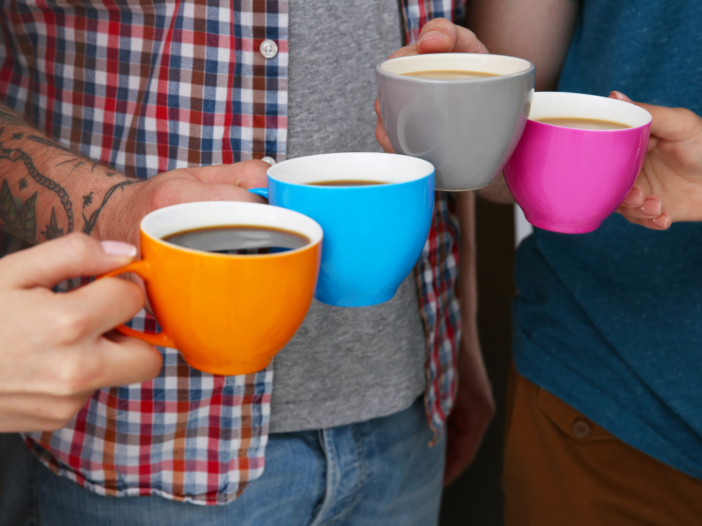 vier mensen hebben allemaal een kopje koffie vast