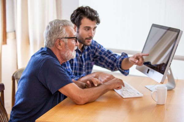 man legt iets uit aan andere man over zijn computer