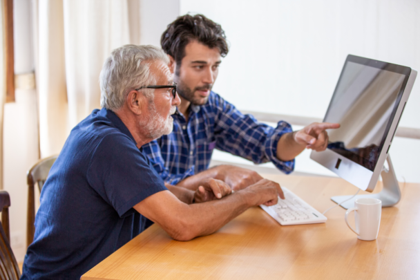 man legt iets uit aan andere man over zijn computer