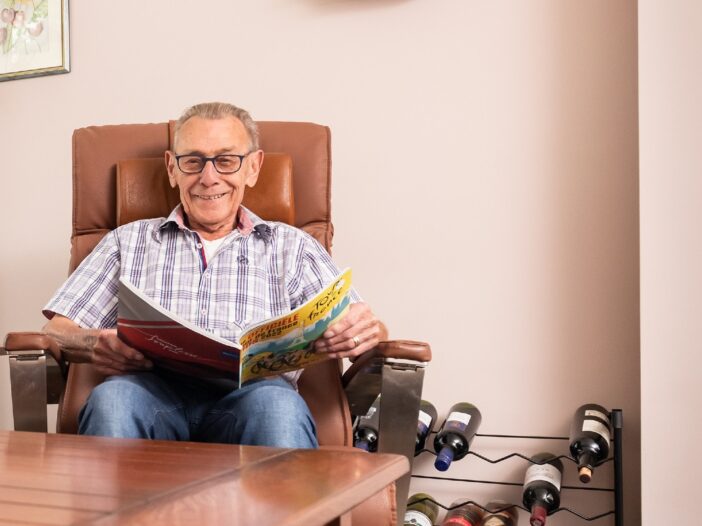 man in stoel aan tafel met een tijdschrift