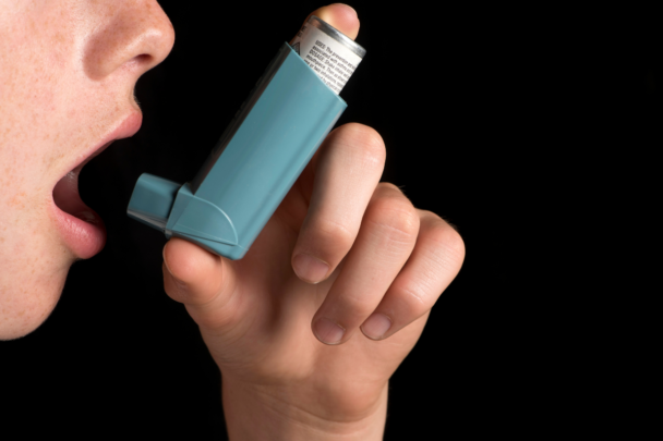 man gebruikt een astma inhaler