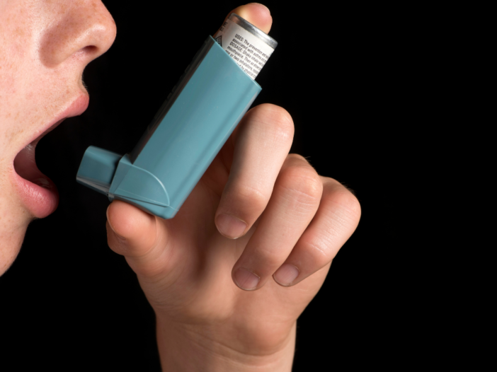 man gebruikt een astma inhaler
