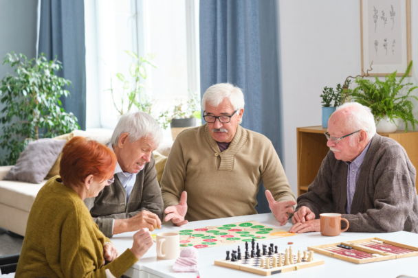 vier ouderen spelen een bordspel aan tafel
