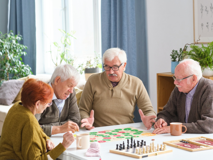 vier ouderen spelen een bordspel aan tafel