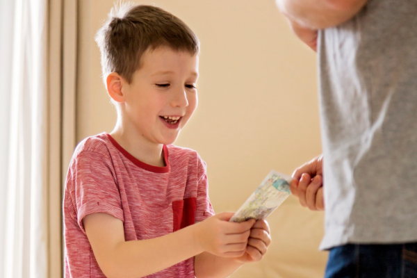 Een jonge jongen krijgt zakgeld van iemand.