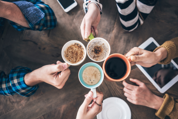 vier mensen houden hun kopje koffie bij elkaar