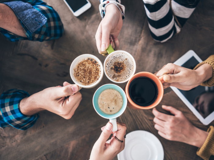 vier mensen houden hun kopje koffie bij elkaar