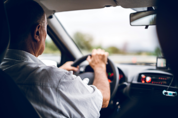 oudere man zit achter het stuur van een auto