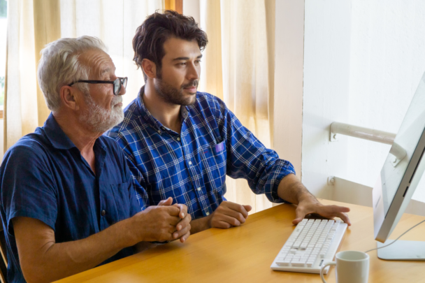 oudere en jongere man gebruiken samen een computer