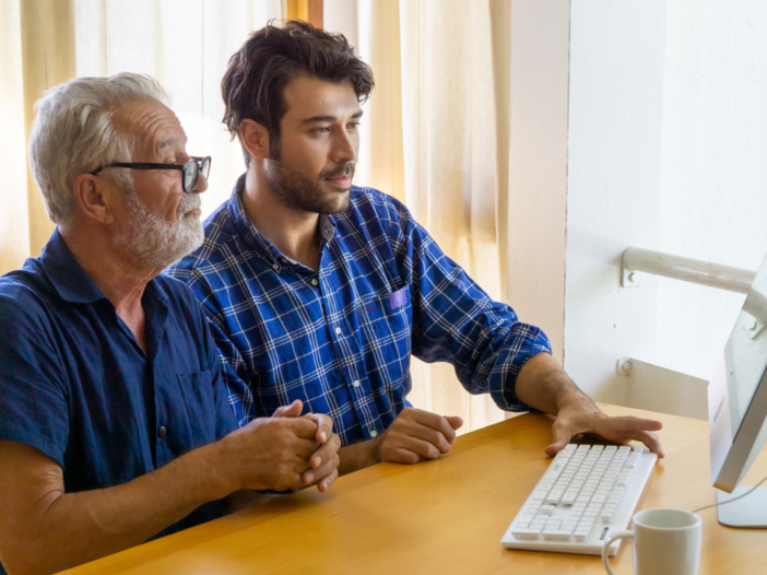 oudere en jongere man gebruiken samen een computer