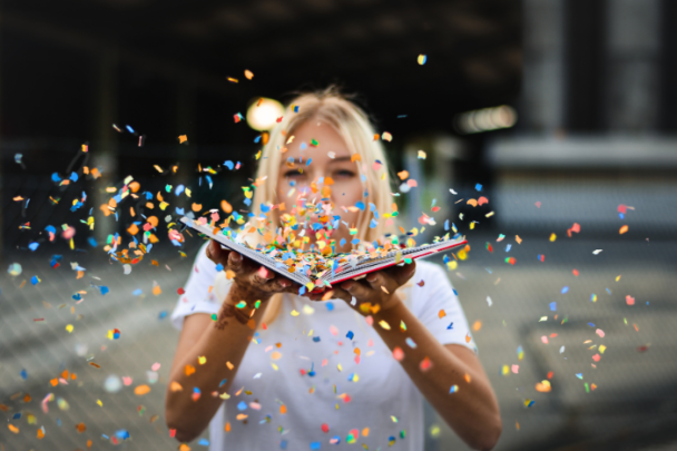 vrouw blaast confetti uit een boek