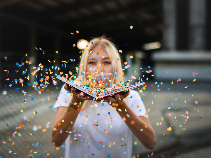 vrouw blaast confetti uit een boek