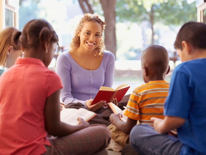 vrouw leest voor aan een groepje kinderen