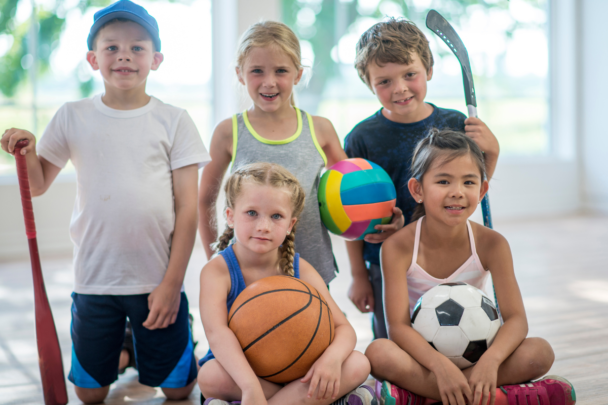 Vijf kinderen poseren voor een foto in sportkleding