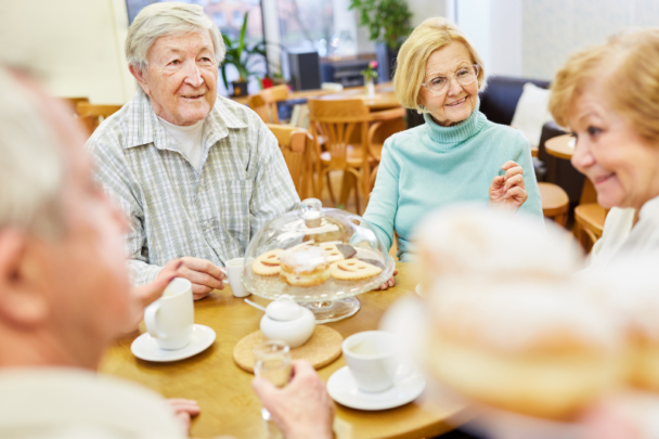 Oudere dames en heer eten samen een maaltijd