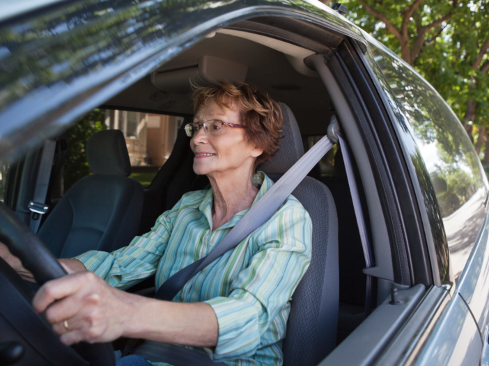 oudere vrouw zit achter het stuur van een auto