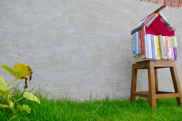 een minibilbiotheek gemaakt van gestapelde boeken, op een grasveldje