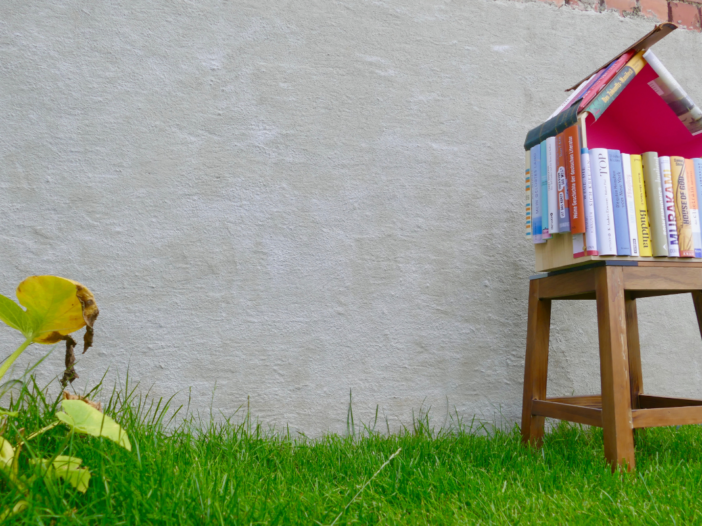 een minibilbiotheek gemaakt van gestapelde boeken, op een grasveldje