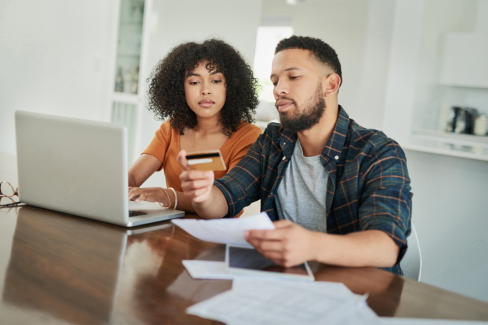 Mensen met schulden die naar hun geldzaken kijken. Voor hun laptop met hun bankpas in hun hand