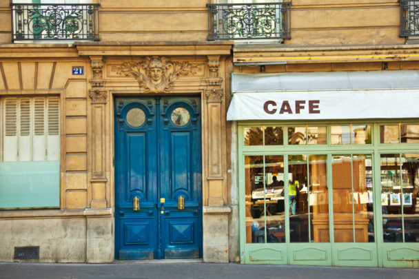 Oud artistiek café met een mooie blauwe deur en een luifel.
