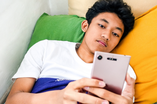 Jongen ligt in bed te scrollen op mijn mobiel
