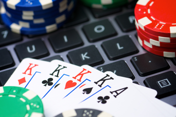 Een toetsenbord van laptop met daarop kaarten en pokermuntjes